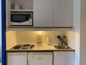 uma pequena cozinha com um micro-ondas e um lavatório em Ref 006 - Appartement 2 pièces à deux pas de la plage et du port, à louer pour les vacances em Arzon