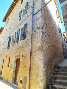 um velho edifício de pedra com persianas azuis em Il Nido di Torri em Sovicille