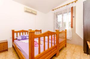 a bedroom with a wooden bed and a window at Apartments Lorena in Stomorska