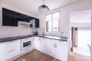 a white kitchen with white cabinets and a sink at House Disney Village in Dammartin-sur-Tigeaux