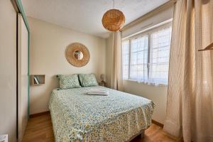 una camera da letto con un letto e una finestra di Les Violettes - Appt à 200 m de la plage a Saint-Aubin-sur-Mer