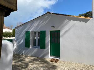 a small white house with green doors and windows at Calme et Tranquillité in Rivedoux-Plage