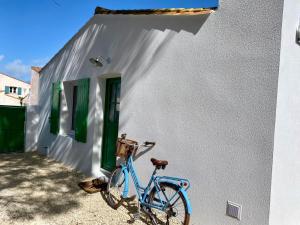 ein blaues Fahrrad, das neben einem weißen Gebäude parkt in der Unterkunft Calme et tranquillité -Ile de Ré in Rivedoux-Plage