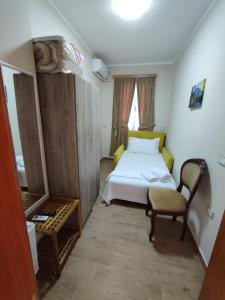 Tékada Hotel & Restaurant في فلوره: غرفة نوم صغيرة بها سرير وكرسي