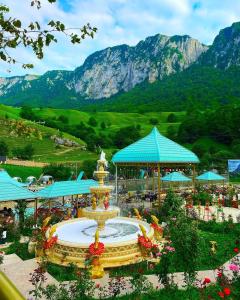 a fountain in a garden with mountains in the background at Mountain Breeze in Qırızdǝhnǝ