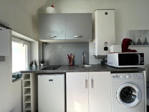 eine Küche mit weißen Schränken und einer Waschmaschine und einem Trockner in der Unterkunft V2 Studio Proche Disney Village Nature in Villiers-sur-Morin