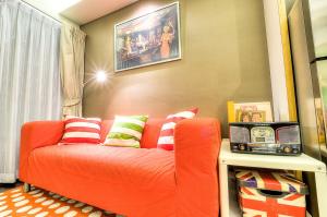 a living room with an orange couch with colorful pillows at The Title Boutique Phuket in Rawai Beach