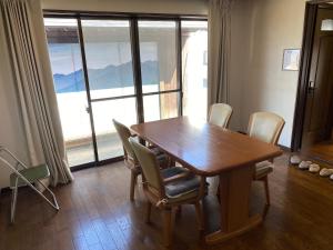 a dining room table with chairs and a large window at ゲストハウスすまいるさん in Iba