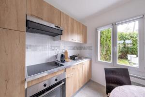 a kitchen with wooden cabinets and a sink and a window at D1 Maison de Charme proche Disney Val d'Europe in Dammartin-sur-Tigeaux +9 photos