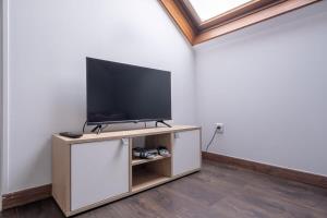 a living room with a flat screen tv on a cabinet at D1 Maison de Charme proche Disney Val d'Europe in Dammartin-sur-Tigeaux