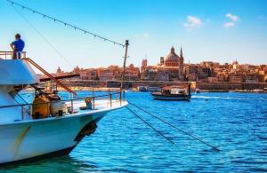 łódź w wodzie z miastem w tle w obiekcie Old Mint Penthouse w mieście Valletta