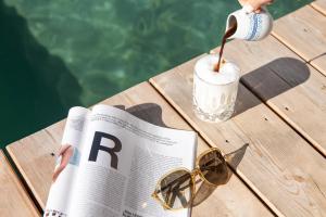 a person reading a newspaper with a drink and sunglasses at Hotel Nesslerhof in Grossarl