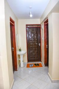 Dala Suites في Kakamega: حمام بباب بني ومغسلة