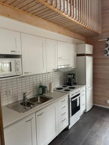 eine Küche mit weißen Schränken, einer Spüle und einer Mikrowelle in der Unterkunft Mökki Jyrkinkuja in Loimaa
