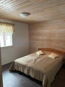 ein Schlafzimmer mit einem Bett mit einer Holzwand in der Unterkunft Mökki Jyrkinkuja in Loimaa