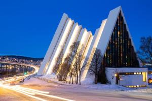 um edifício na neve ao lado de uma rua em Sentralt beliggende leilighet ved Fjellheisen - Tromsø em Tromsø