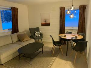 uma sala de estar com um sofá, uma mesa e cadeiras em Sentralt beliggende leilighet ved Fjellheisen - Tromsø em Tromsø