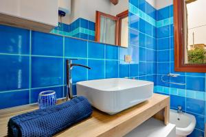 a blue tiled bathroom with a sink and a toilet at Villa Quattro Cuori in San Teodoro +16 photos