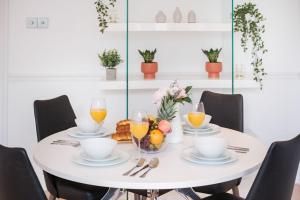 uma mesa branca com uma taça de fruta e copos de sumo de laranja em London Fitzrovia CityApartmentStay em Londres