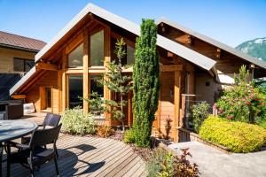 a house with a deck with a table and chairs at Les Tr&eacute;soms Lake and Spa Resort in Annecy