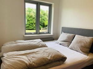 an unmade bed in a bedroom with a window at Beautiful villa close to beach and nature in Hanstholm