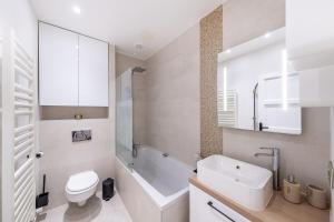 La salle de bains est pourvue d'une baignoire blanche, de toilettes et d'un lavabo. dans l'établissement Appartement Prestige Champs Elysées, à Suresnes