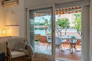 a living room with a door open to a patio with a table at Canela Homes COSTA CASA AILA in Castelldefels
