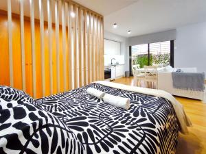 a bedroom with a black and white bed and a kitchen at Moderno apartamento tipo loft en Terrassa centro in Terrassa