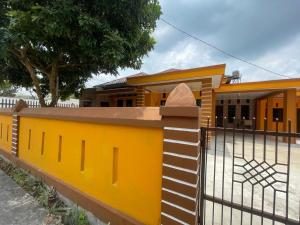 una cerca amarilla frente a una casa en OYO 93866 Neva Guest House Syariah en Parit