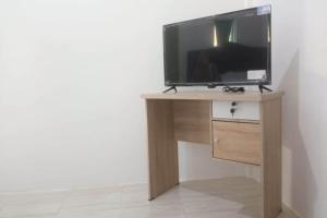 TV sobre una mesa de madera en OYO 93866 Neva Guest House Syariah en Parit