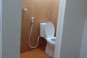 a bathroom with a toilet with a shower nozzle at OYO 93866 Neva Guest House Syariah in Parit