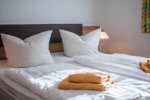 two beds with white sheets and pillows with towels on them at Gasthof Blankenberg 