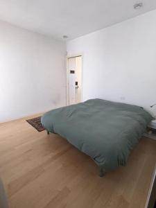 a bed in a white room with a wooden floor at Appartamento Ilaria in Dueville