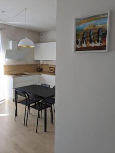 una cocina con mesa negra, sillas y una pintura en Appartamento Ilaria, en Dueville