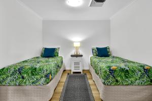 two beds sitting next to each other in a room at Iluka Resort Apartments Palm Beach in Palm Beach