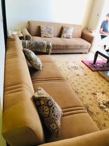 a living room with a brown couch with pillows at شاليه in El Alamein