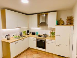 a kitchen with white cabinets and a stove top oven at Traumhafte 115 qm Ferienwohnung am Steinhuder Meer, Ruhig, Komfortabel, Loggia, Parkplatz, WiFi in Wunstorf