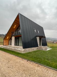 a house with a black roof on top of a field at Elviu Guesthouse in Lacu Rosu