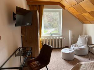 ターレにあるPension Sternschnuppe, Treseburg Harz, unmittelbar am Wasserのテレビ、椅子、窓が備わる客室です。