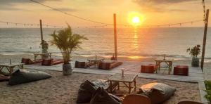 a sunset on the beach with tables and chairs at Scandinavian Beach Resort in Ko Lanta