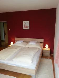 Schlafzimmer mit einem großen weißen Bett und einer roten Wand in der Unterkunft Ferienwohnung in ruhiger Lage am Waldrand - b55795 in Navis