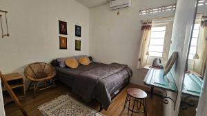 a bedroom with a bed and a chair and a window at Oke Baik Hostel in Yogyakarta