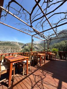 a deck with wooden tables and chairs and mountains at Faralya Misafir Evi in Faralya