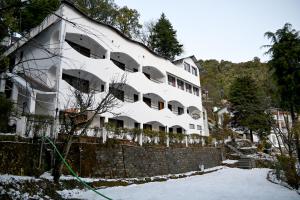 a white building with a fence in the snow at Kumaon Roop Resort Near Neem Karoli Temple in Nainital
