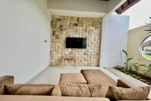 a living room with a couch and a stone wall at Belvilla 93823 Villa Gan Near Titi Batu Club Ubud in Ubud