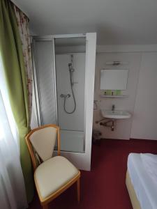 a bathroom with a shower and a chair and a sink at Room in Guest room - Pension Forelle - double room 01 in Forbach