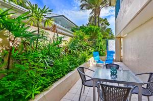 a patio with tables and chairs and palm trees at Iluka Resort Apartments Palm Beach in Palm Beach +11 photos