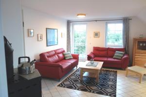ein Wohnzimmer mit zwei roten Sofas und einem Tisch in der Unterkunft Mina in Fehmarn