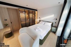 een slaapkamer met een wit bed en een stoel bij The AHouse High-End Interior Design Building in Ho Chi Minh-stad