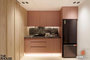 a kitchen with brown cabinets and a black refrigerator at The AHouse Building in Ho Chi Minh City